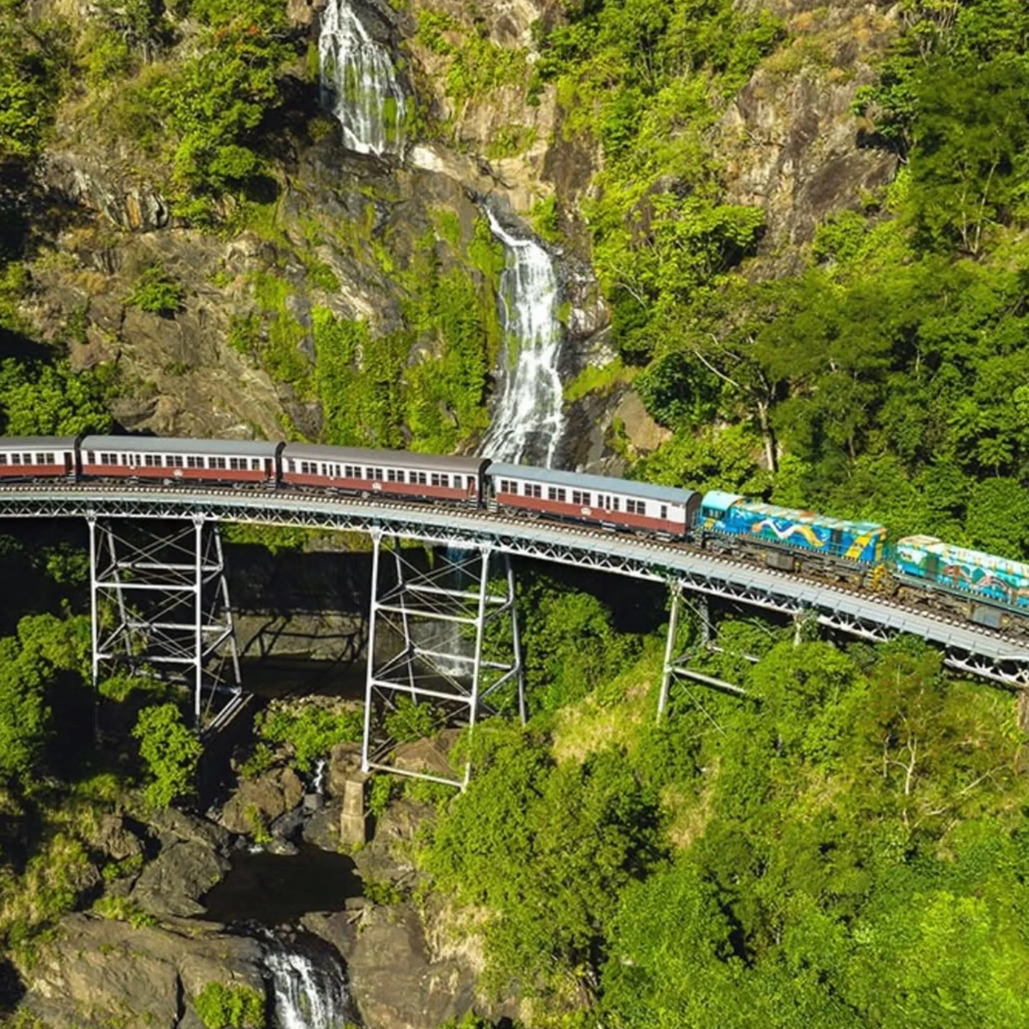 heritage train beside rainforest waterfalls